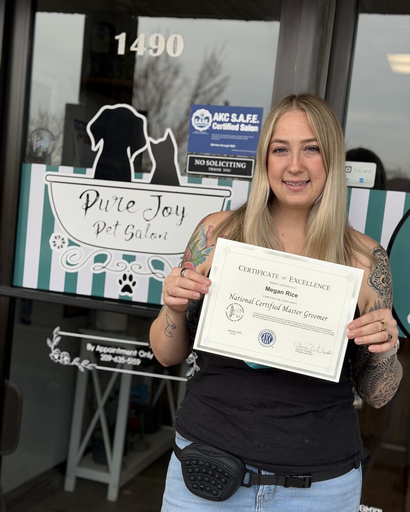 Megan Rice holding her National Certified Master Groomer certificate at Pure Joy Pet Salon