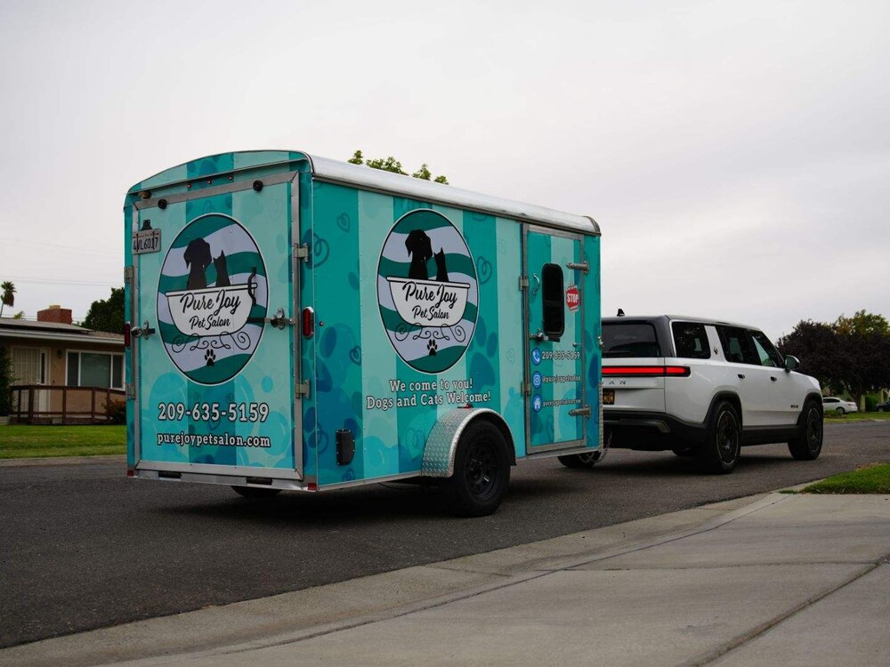 The wrapped Pure Joy mobile grooming trailer with logo and phone number