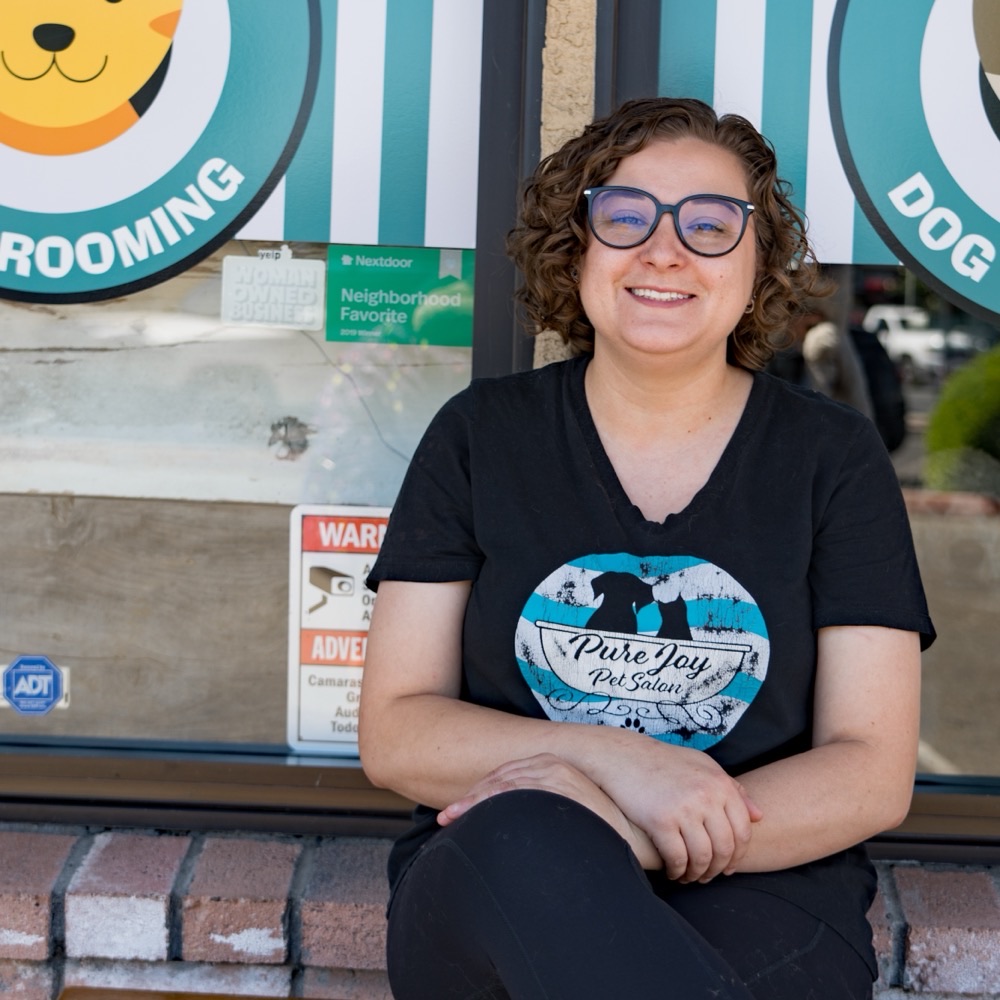 Nichole, pet stylist at Pure Joy Pet Salon, smiling outside the Atwater salon